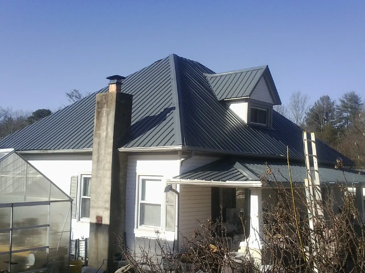 Dark blue standing seam metal roof on a white farmhouse with dormer — Slate & Tile Roof Repair by Roofing Brothers in Milpitas