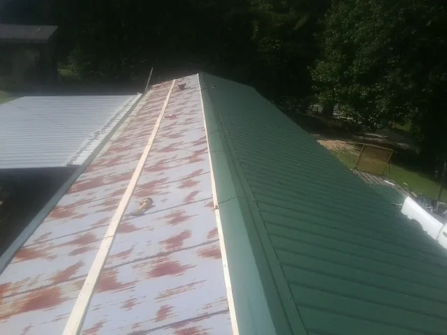 Old rusted panels beside newly installed green metal roofing — Wind Damage Roof Repair by Roofing Brothers in Milpitas
