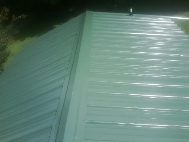 New green metal panels meeting at the ridge of a roof — Flat Roof Repair work by our crew in Milpitas